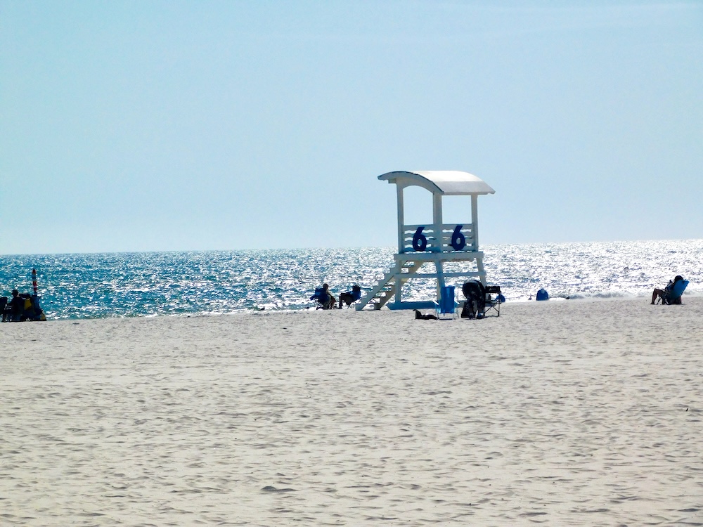 The beach at gulf shores off-season, with empty lifeguard hut and scattered people.