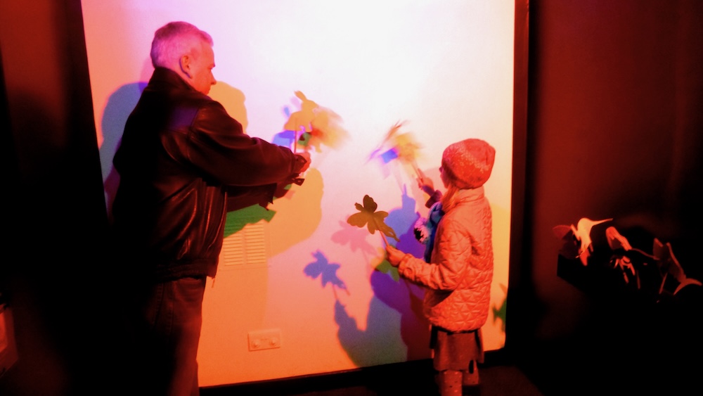 dad and daughter create shadows with puppets at the camera obscura museum.