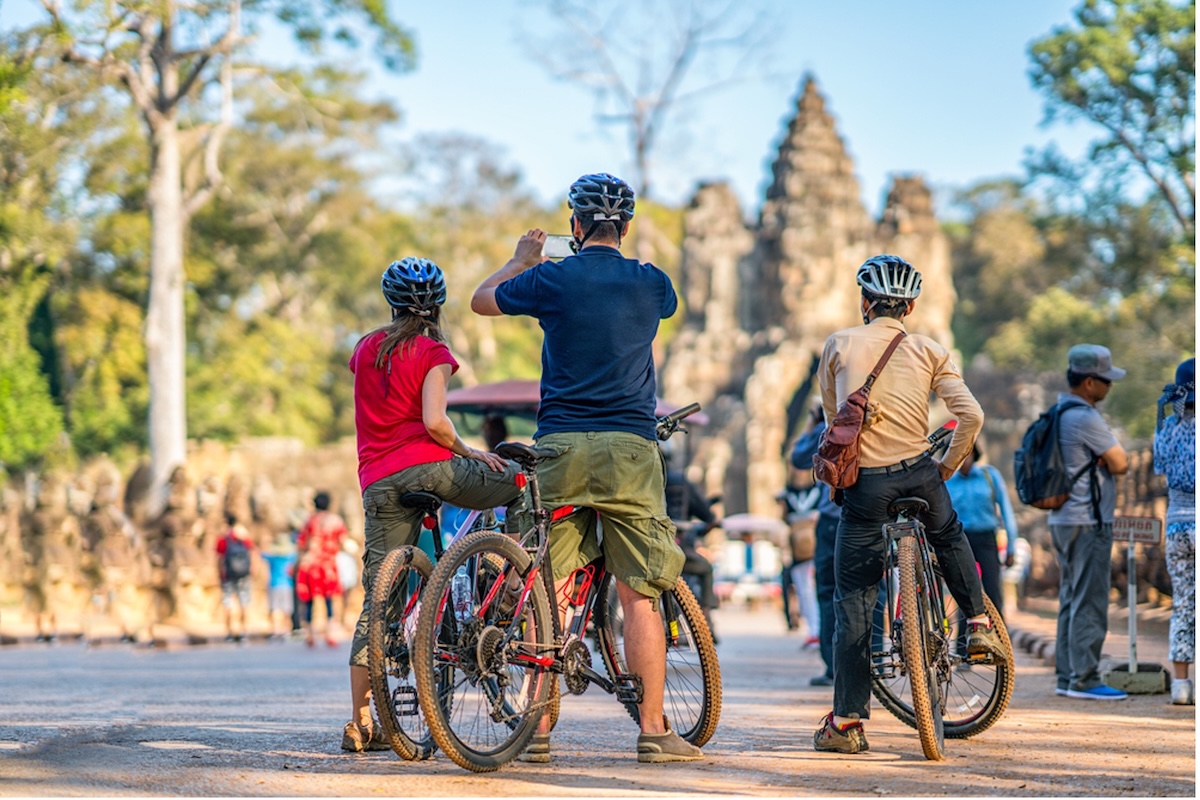 4 Suprising Places to Ride Bicycles in Cambodia With Kids: A family pauses during a bike ride around Angkor Wat, to take photos of one of its many temples.